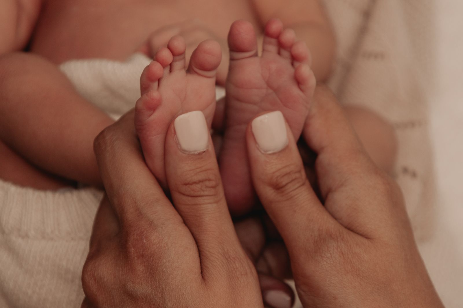 Hands gently holding a newborn baby's feet